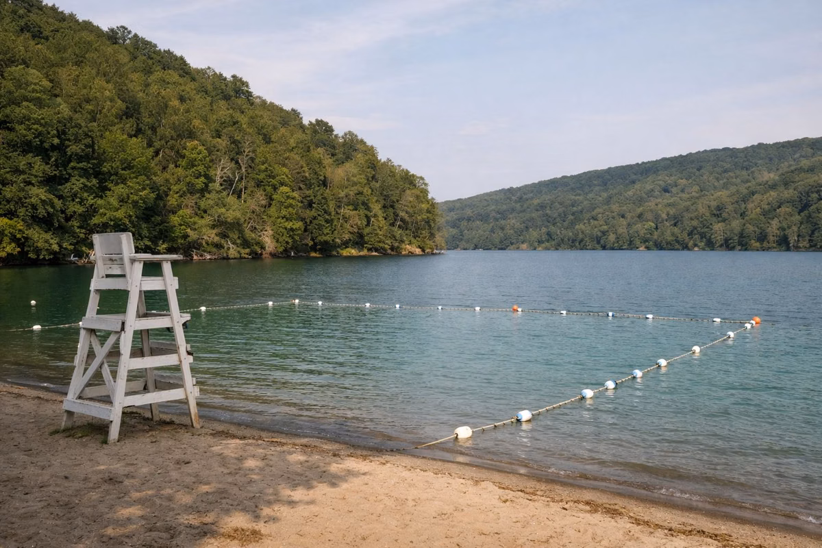 A roped swimming area and lifeguard chair on a sandy lake beach
