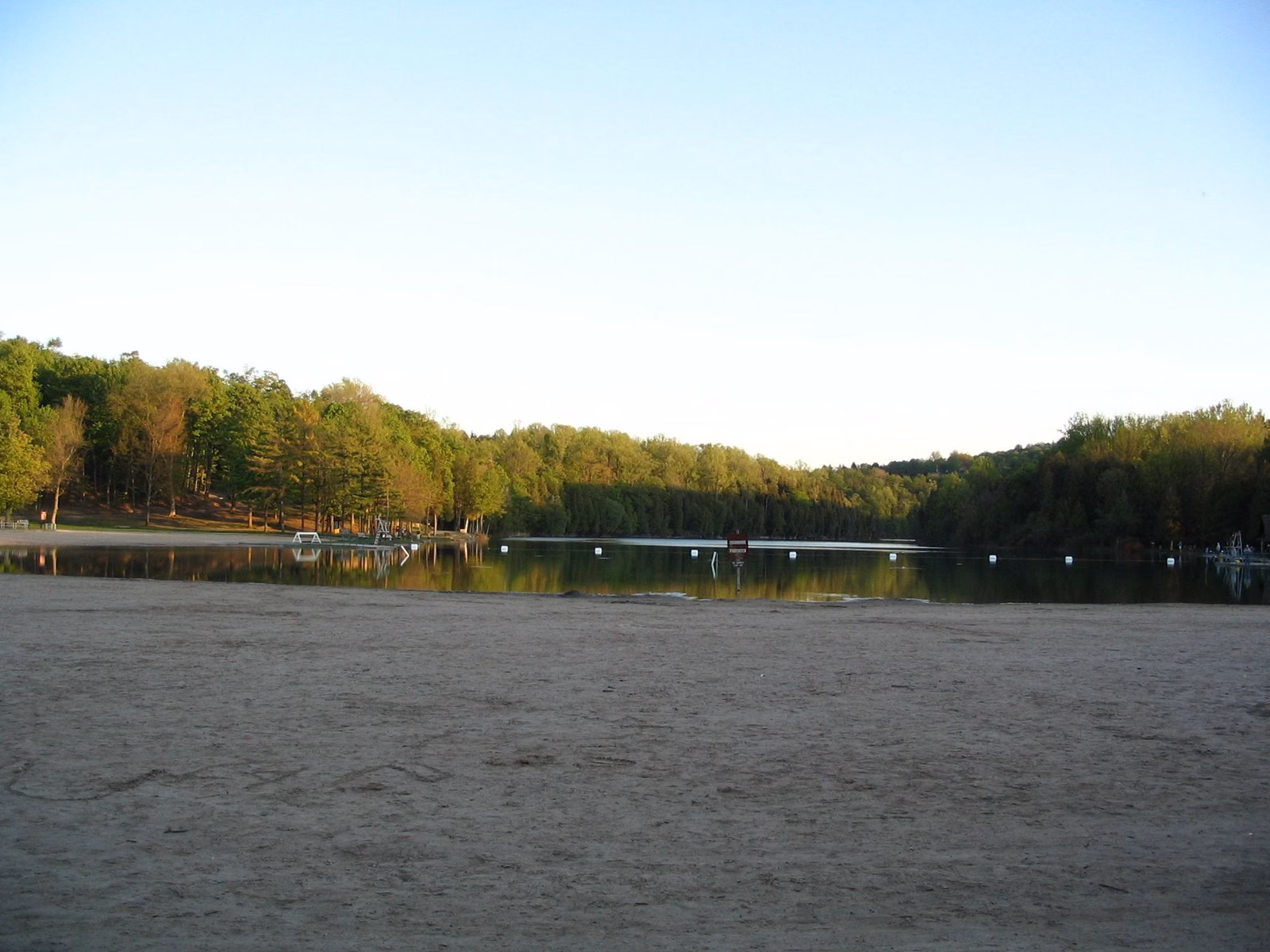 The sand swimming beach on Green Lake with wooded hills behind
