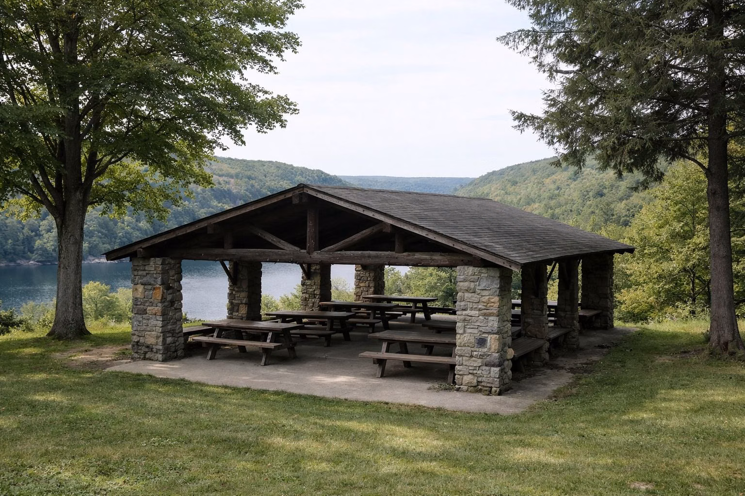 A rustic stone and timber picnic pavilion on a grassy hill